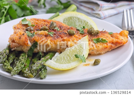 Haddock fish piccata, battered fish fillet with capers and lemon, served with asparagus, horizontal Haddock fish piccata, battered fish fillet with capers and lemon, served with asparagus, horizontal 136529814