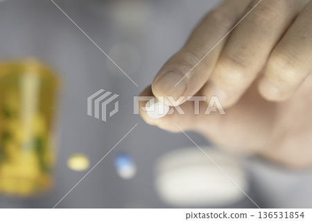 特寫鏡頭:服用前用手指捏住一顆白色藥丸。 特寫鏡頭:服用前用手指捏住一顆白色藥丸。 136531854