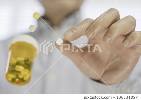 特寫鏡頭:服用前用手指捏住一顆白色藥丸。 特寫鏡頭:服用前用手指捏住一顆白色藥丸。 136531857