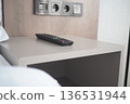 Remote control on a nightstand next to a bed 136531944