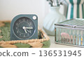 Modern clock in a basket next to other items on a table 136531945