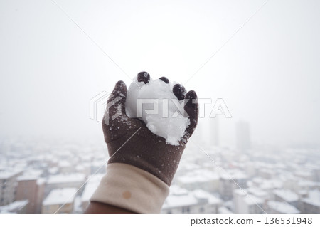 Snowball in hand during winter in city 136531948