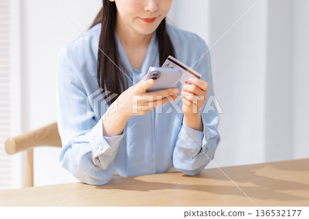 一名女子手持信用卡和智慧型手機 一名女子手持信用卡和智慧型手機 136532177