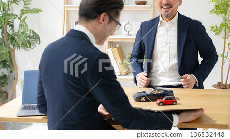 Male car dealer negotiating Male car dealer negotiating 136532448