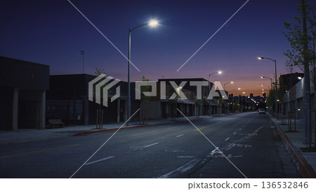 Quiet Downtown Street at Dusk with Streetlights and Purple Sunset Sky 136532846