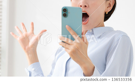 一個女人驚訝地看到一部智能手機 136533356