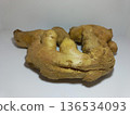 Fresh Ginger Root on White Surface  Close-up of a fresh ginger root placed on a clean white surface with a plain white background. The ginger features a rough, tan-colored skin with knobby protrusions 136534093