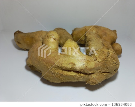 Fresh Ginger Root on White Surface Close-up of a fresh ginger root placed on a clean white surface with a plain white background. The ginger features a rough, tan-colored skin with knobby protrusions Fresh Ginger Root on White Surface Close-up of a fresh ginger root placed on a clean white surface with a plain white background. The ginger features a rough, tan-colored skin with knobby protrusions 136534093