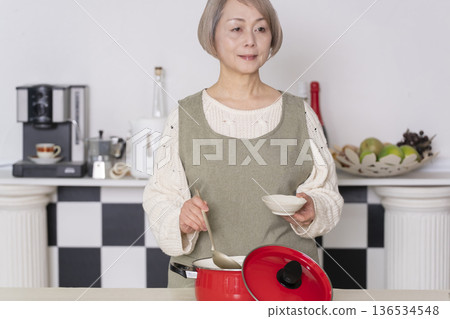 Senior woman tasting the food she cooked in the kitchen Senior woman tasting the food she cooked in the kitchen 136534548