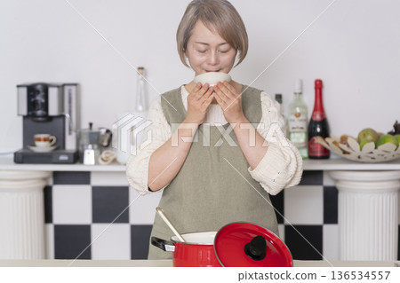 一位老婦人在廚房品嚐自己做的餐點。 一位老婦人在廚房品嚐自己做的餐點。 136534557