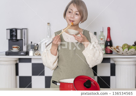Senior woman tasting the food she cooked in the kitchen 136534565
