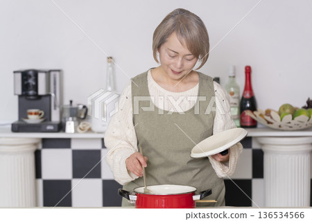 Senior woman tasting the food she cooked in the kitchen Senior woman tasting the food she cooked in the kitchen 136534566