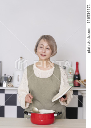 Senior woman tasting the food she cooked in the kitchen 136534571