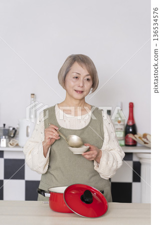Senior woman tasting the food she cooked in the kitchen 136534576