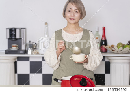 Senior woman tasting the food she cooked in the kitchen Senior woman tasting the food she cooked in the kitchen 136534592