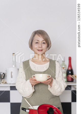 Senior woman tasting the food she cooked in the kitchen 136534599