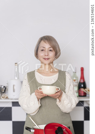 Senior woman tasting the food she cooked in the kitchen 136534601