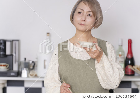Senior woman tasting the food she cooked in the kitchen Senior woman tasting the food she cooked in the kitchen 136534604