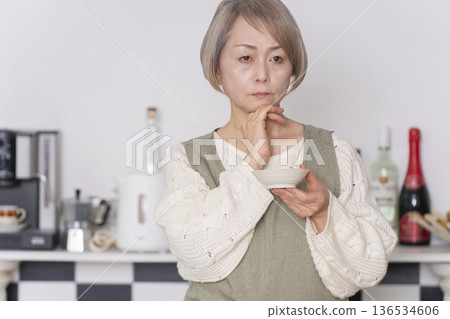 Senior woman tasting the food she cooked in the kitchen Senior woman tasting the food she cooked in the kitchen 136534606