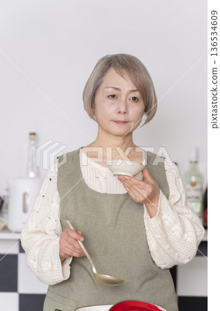 Senior woman tasting the food she cooked in the kitchen 136534609