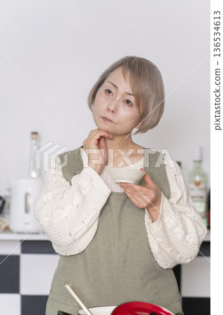 一位老婦人在廚房品嚐自己做的餐點。 136534613