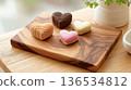 Heart-shaped chocolates and cookies lined up on a wooden plate Valentine's Day image 136534812