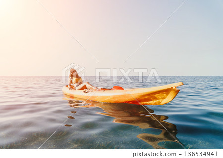 Woman Kayaking Ocean Summer - A woman enjoys a relaxing kayak ride on a calm ocean on a sunny summer day. Woman Kayaking Ocean Summer - A woman enjoys a relaxing kayak ride on a calm ocean on a sunny summer day. 136534941