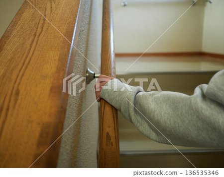 A child walking up the stairs holding onto the indoor handrail A child walking up the stairs holding onto the indoor handrail 136535346
