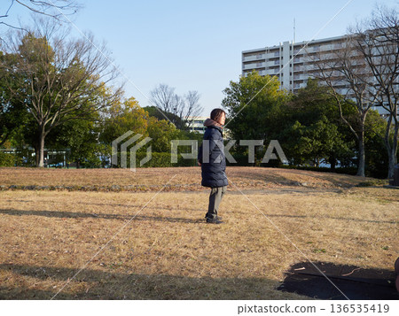 冬日午後,一位中年家庭主婦在公園散步。 冬日午後,一位中年家庭主婦在公園散步。 136535419