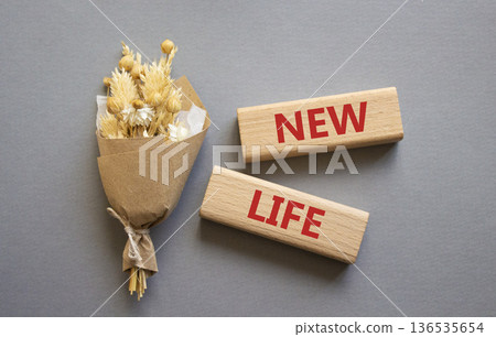 New life symbol. Concept word New life on wooden blocks. Beautiful grey background with bouquet of flowers. Business and New life concept. Copy space New life symbol. Concept word New life on wooden blocks. Beautiful grey background with bouquet of flowers. Business and New life concept. Copy space 136535654