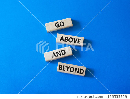 Go above and beyond symbol. Concept words Go above and beyond on wooden blocks. Beautiful bright blue background. Business and Go above and beyond concept. Copy space. Go above and beyond symbol. Concept words Go above and beyond on wooden blocks. Beautiful bright blue background. Business and Go above and beyond concept. Copy space. 136535729