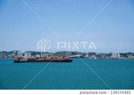 一艘貨船駛過海峽，藍天白雲。 136535985
