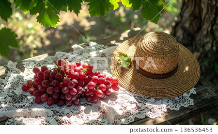 Red Grapes with Straw Hat on Rustic Wooden Table 136536453