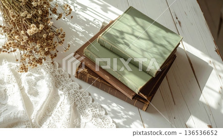 Vintage Green and Brown Book Stack on White Desk with Lace Cloth Vintage Green and Brown Book Stack on White Desk with Lace Cloth 136536652