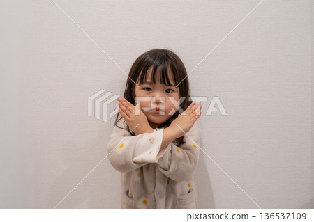 一個孩子雙臂交叉，雙手比劃成十字。 136537109