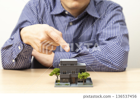 A man's hand pointing at a house 136537456
