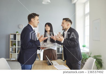 Business colleagues arguing in modern office while female mediator calms dispute Business colleagues arguing in modern office while female mediator calms dispute 136537492