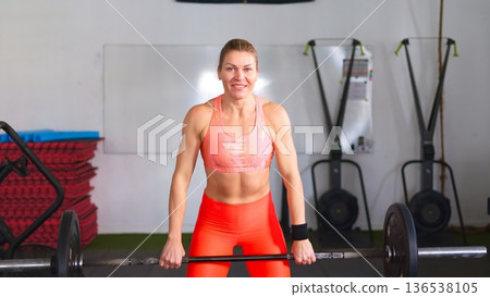 Woman lifting barbell in gym enjoying with the training 136538105