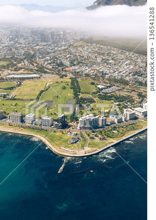 Aerial view of Cape Town cityscape, ocean coastline, and green golf course under cloudy sky. Luxury travel and tourism in South Africa. 136541288