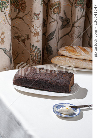 Rye bread loaf on white plate indoors 136541547