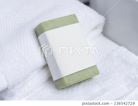 Green soap bar with blank label on white bath towels near basin, natural hygiene product mockup Green soap bar with blank label on white bath towels near basin, natural hygiene product mockup 136542729