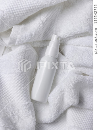 Mockup of white blank spray cosmetic bottle on white bath terry towel for spa hotel use 136542733
