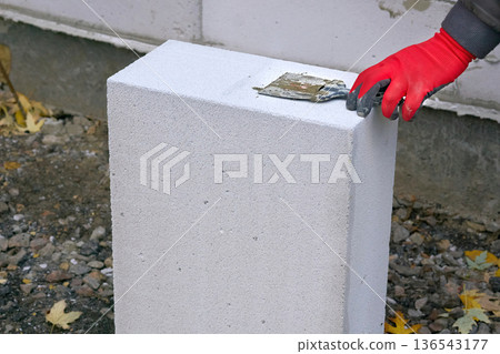 Workers hand in a protective glove holding a trowel Workers hand in a protective glove holding a trowel 136543177