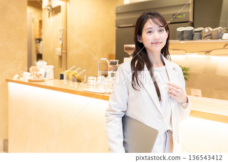 Young woman standing with a laptop in a cafe Young woman standing with a laptop in a cafe 136543412
