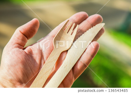A pair of wooden cutlery fork and knife in hand on bokeh nature background A pair of wooden cutlery fork and knife in hand on bokeh nature background 136543485