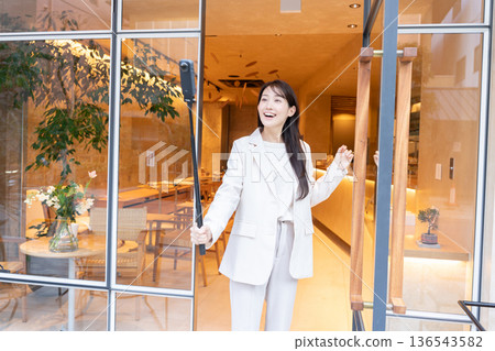 A young woman streaming video with a 360-degree camera at the entrance of a cafe A young woman streaming video with a 360-degree camera at the entrance of a cafe 136543582