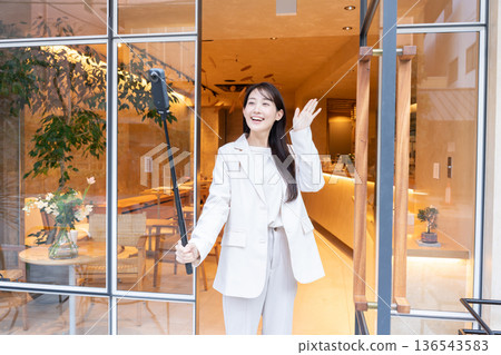 A young woman streaming video with a 360-degree camera at the entrance of a cafe A young woman streaming video with a 360-degree camera at the entrance of a cafe 136543583