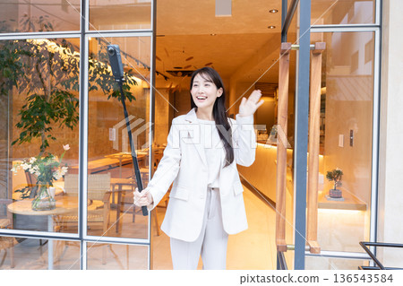 A young woman streaming video with a 360-degree camera at the entrance of a cafe A young woman streaming video with a 360-degree camera at the entrance of a cafe 136543584