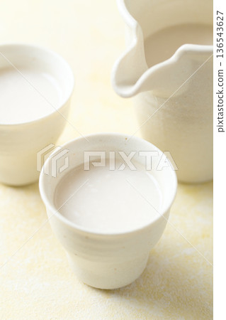 用麴菌釀造的甜酒倒入小杯中 用麴菌釀造的甜酒倒入小杯中 136543627
