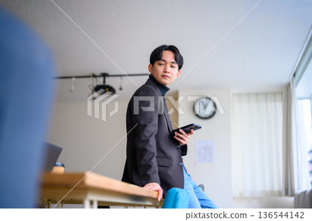 Man holding a mobile phone indoors Man holding a mobile phone indoors 136544142